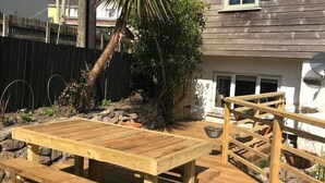Een houten terras met een picknicktafel en een kleine houten trap naar een huis.