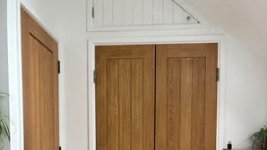Een kamer met een houten garderobe, een klein houten dressoir en een beigekleurig tapijt.