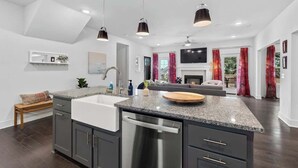 Une cuisine moderne dotée de plans de travail en granit, d’appareils électroménagers en acier inoxydable et de luminaires suspendus.