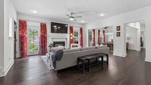 Un salon spacieux avec un grand canapé, une cheminée et un ventilateur de plafond.