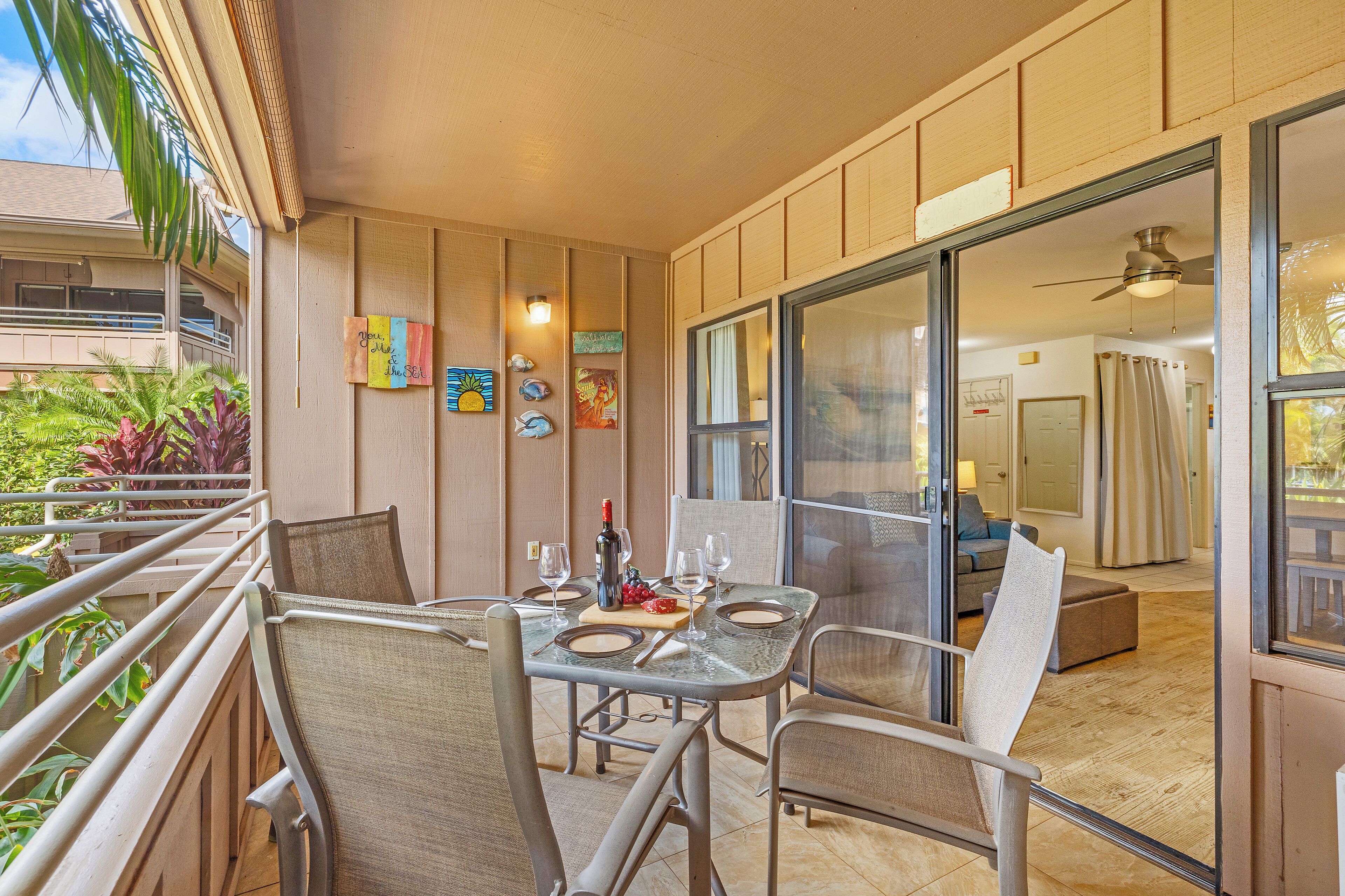 Un balcón con mesa lista para comer, sillas y vista al interior.