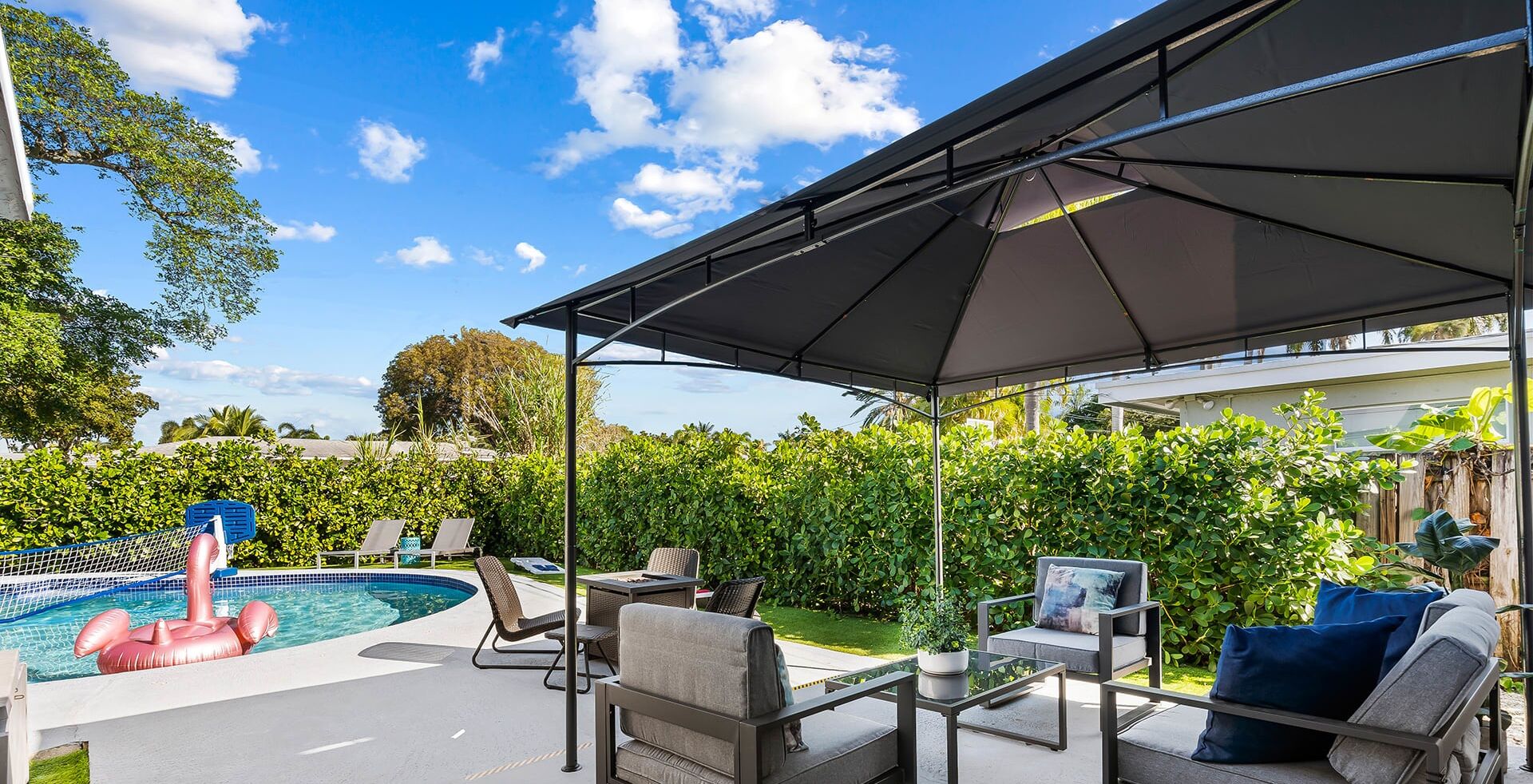 Un espace extérieur abrité, aménagé avec une piscine, des chaises longues et une table.