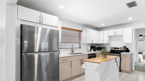 A modern kitchen with stainless steel appliances, white cabinetry, and a wooden island. - Private Heated Pool & Lovely Home (Dania Beach)