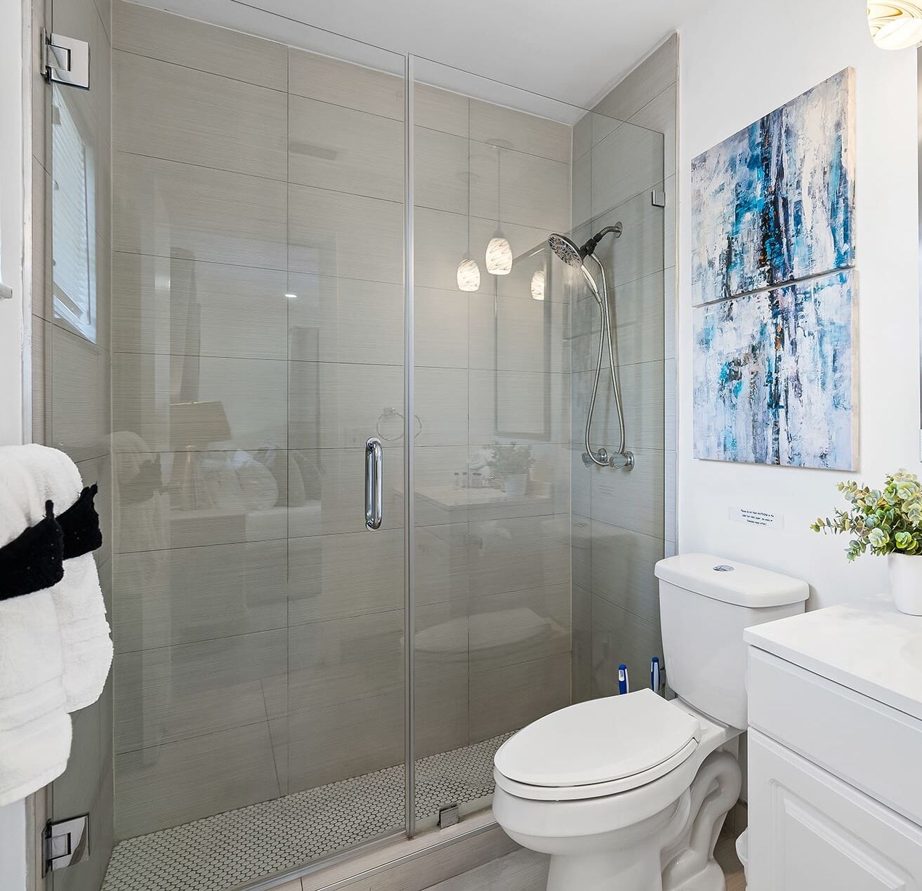 Une salle de bain moderne avec une douche à parois de verre, des toilettes blanches et un lavabo doté d’un plan de travail blanc.