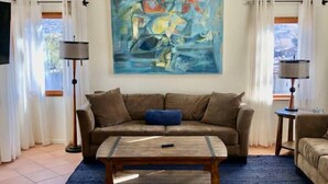 A living room with a brown sofa, a blue rug, a wooden coffee table, and a large abstract painting on the wall. - Wild Horse Country Stay • Mt. Rose Views Near Reno (Reno)