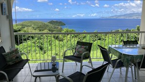 A balcony with a view of the sea and hills, furnished with chairs and a table. - L'Oiseau Bleu - 1bed - 4p - Sea view - Beach 600m (Les Trois-Îlets)