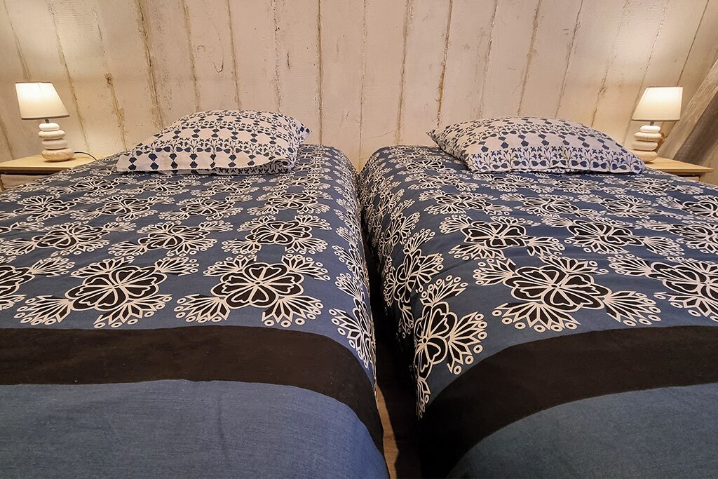 Deux lits avec une parure de lit assortie à motifs floraux et des tables de chevet avec des lampes.