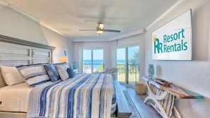 Una camera da letto con un letto, una ventola a soffitto, vista sull'oceano e un cartello per Resort Rentals.