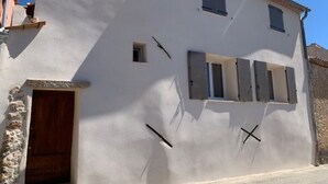 Un edificio blanco con base de piedra, puerta de madera y una ventana pequeña.