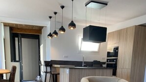 Una sala de estar moderna con una mesa de centro de madera, un sillón de cuero y una cocina al fondo.