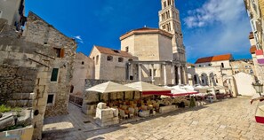 A historic square with stone buildings, a prominent tower, and outdoor seating areas with umbrellas. - Modern 90 m2 apt With Balcony w the sea View (Split)