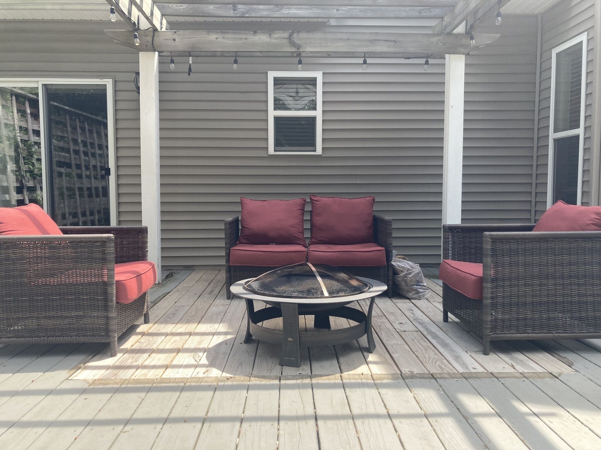 A covered patio with wicker furniture, a round table, and a small fire pit.