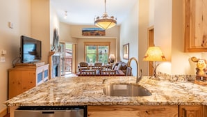 A kitchen with granite countertops, a stainless steel sink, a dishwasher, and a television on a wooden cabinet. - Perfect views of the Super Bee Lift, Free WiFi, underground parking (Copper Mountain)