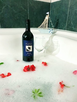 A bottle of Plavac Mali wine, two glasses, and a decorative item in a bathtub filled with bubbles and red flowers. - Large 120 m2 apt With Patio,1 min Walk From Beach (Dugi Rat)