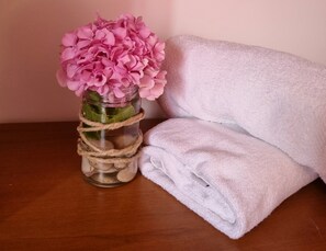 A wooden table with a glass vase containing pink flowers, wrapped with twine, and a folded white towel beside it. - Large 120 m2 apt With Patio,1 min Walk From Beach (Dugi Rat)