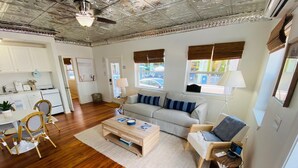 A spacious living area with a wooden floor, a sofa, a coffee table, and a dining area with chairs and a table.