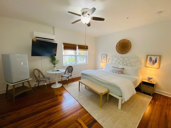 A bedroom with a bed, a desk, a chair, a TV, and a ceiling fan.