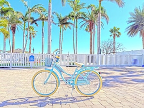 Bicycles may be parked in this secure area, surrounded by palm trees and an entrance.