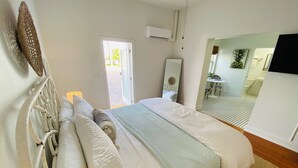 A neatly arranged bedroom with a bed, a bedside lamp, and a view of the bathroom.