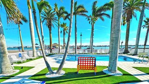 A poolside area with palm trees, a red netted structure, and lounge chairs.