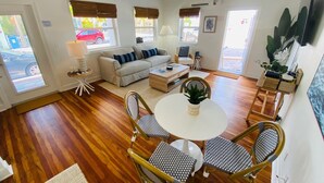 A cozy living room with a sofa, coffee table, and dining area with chairs.