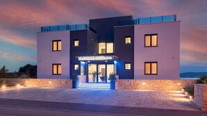Un hotel moderno con fachada de piedra, un letrero que dice "VILLE VAN & MARIA" y una entrada bien iluminada.