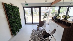 A reception area with a green wall, a seating area with a table and chairs, a patterned rug, and a wooden counter with flowers. - Villa Ivan pool apartament (Sv. Filip I Jakov)