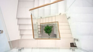 A modern interior with a glass staircase, a central plant, and a minimalist design. - Villa Ivan pool apartament (Sv. Filip I Jakov)