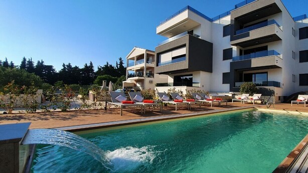 A modern building with a pool and sun loungers. - Villa Ivan pool apartament (Sv. Filip I Jakov)