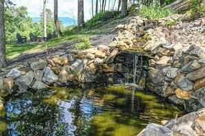 Uma cascata de pedra natural, um pequeno lago e uma área de estar com cadeiras.