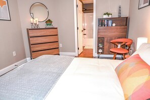 A bedroom with a bed, a dresser, a chair, a bookshelf, and a mirror. - Barefoot in the Blue Ridge (Hayesville)