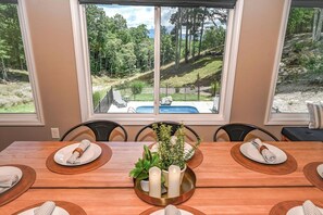 A dining area with a view of a swimming pool and trees. - Barefoot in the Blue Ridge (Hayesville)
