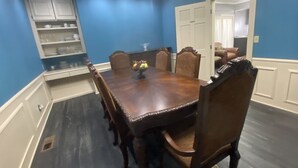 A dining room with a wooden table and chairs, blue walls, and a white door.