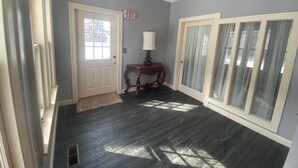 A hallway with a door, a lamp, and a window with curtains.