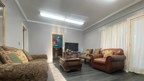 A living room with a patterned sofa, a leather armchair, and a wooden coffee table.