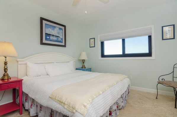 Un dormitorio con una cama, una mesita de noche, una silla, una ventana y un cuadro en la pared.