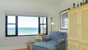 Ein Zimmer mit Blick auf den Ozean, ein graues Sofa, ein kleiner Tisch mit einem Korb und ein gelbes Sideboard.