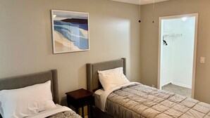 A bedroom with two beds, a ceiling fan, a painting on the wall, and a door leading to another room. - Grand Deluxe Garden 3BR Penthouse near Disney Parks (Kissimmee)