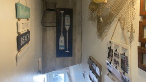 A hallway with a welcome sign, a wooden door, and a wall decorated with nautical items and photographs. - North Shore Loft, close to everything! (Clear Lake)
