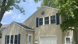 A two-story house with beige siding, blue shutters, and a white garage door. - North Shore Loft, close to everything! (Clear Lake)