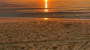 A beach with footprints leading to the water, a sunset, and a cloudy sky. - Agréable Maison Bois (Andernos-les-Bains)