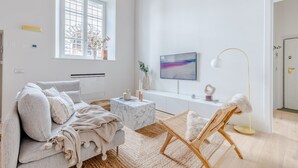 Una sala de estar moderna con un sofá, una mesa de centro, una silla, un televisor y una lámpara de pie.