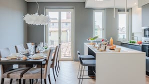 A modern kitchen with a dining area, large windows, and a view of the city.