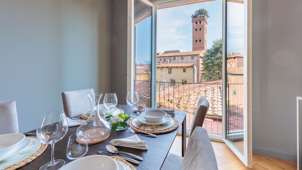 A dining table set for four with a view of a historic tower through a glass door.