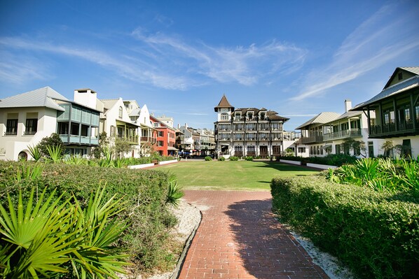 A pathway leading to a building with a central tower, surrounded by lush greenery and other buildings. - Gulfside Rosemary "Freedom Carriage House" |Studio |Sleeps 4 | 2 Bikes (Rosemary Beach)