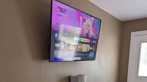 A small kitchenette with a microwave, coffee maker, and a TV mounted on the wall. - The Greenland Motel - Room No. 7 (Munising)