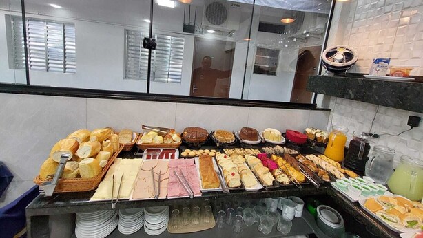 A buffet with various food items and utensils. - Pousada Itaguaçu (Aparecida)