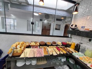 A buffet with various food items and utensils. - Pousada Itaguaçu (Aparecida)