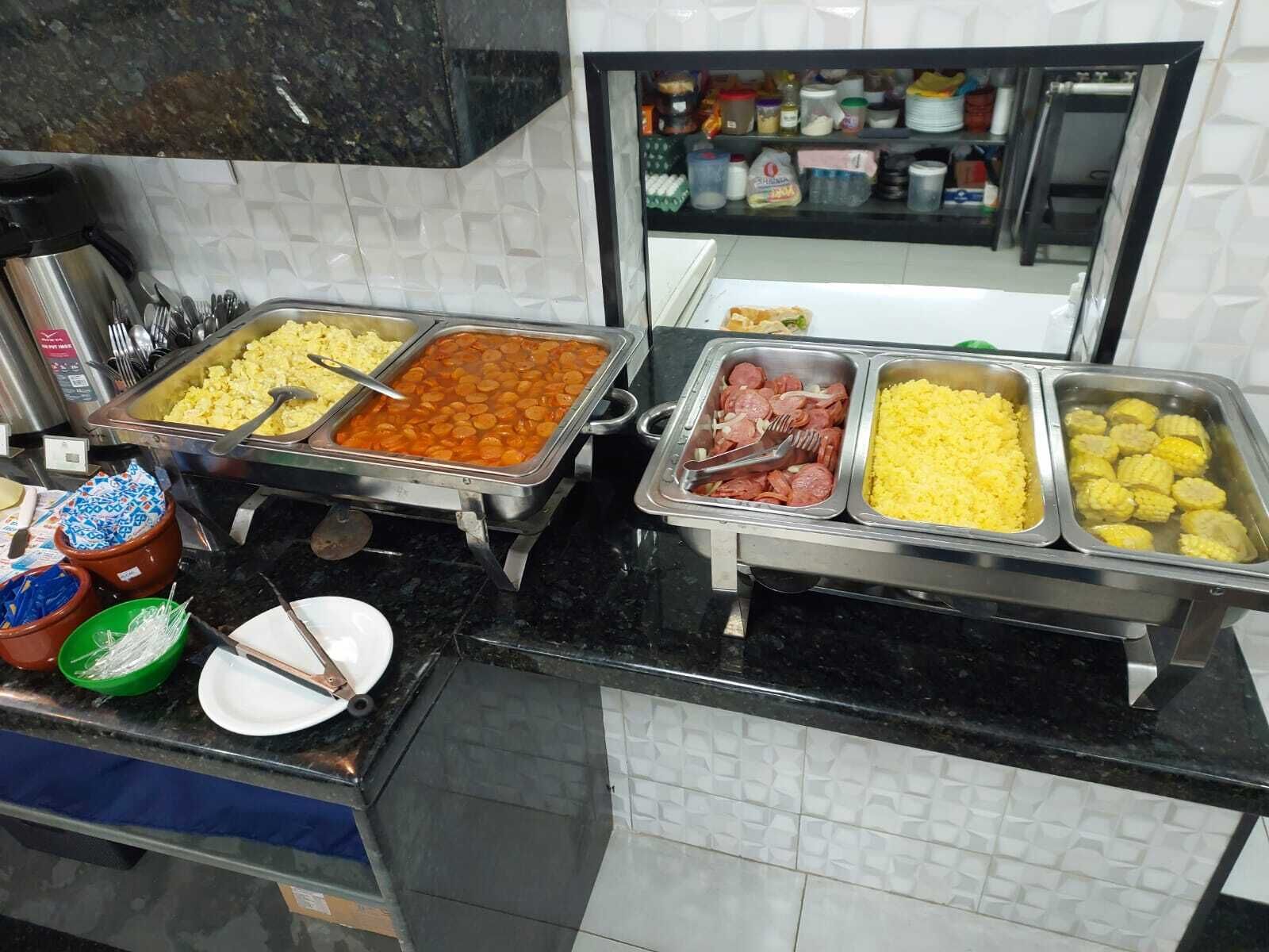 Un buffet con diverse opzioni di cibo, tra cui patate, salsicce e mais.