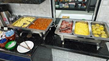 Un buffet con diverse opzioni di cibo, tra cui patate, salsicce e mais.